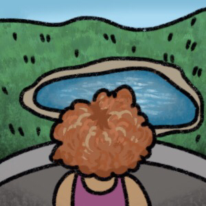 a person looking over some forested hills and a lake. They stand by a stone wall. They have curly red hair and a magenta tank top.